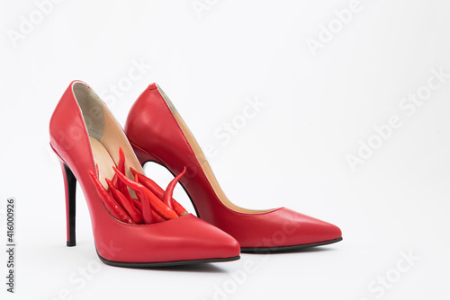 Bright red women's stiletto heels. There are chili peppers nearby. Nice combination of shoes and pepper. Red color