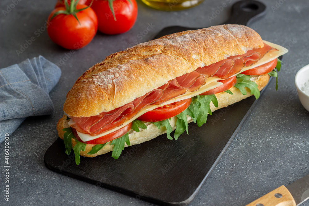 Sandwich with prosciutto, tomatoes, arugula and cheese. Healthy eating. Diet. Sandwich with prosciutto, tomatoes, arugula and cheese. Healthy eating. Diet.