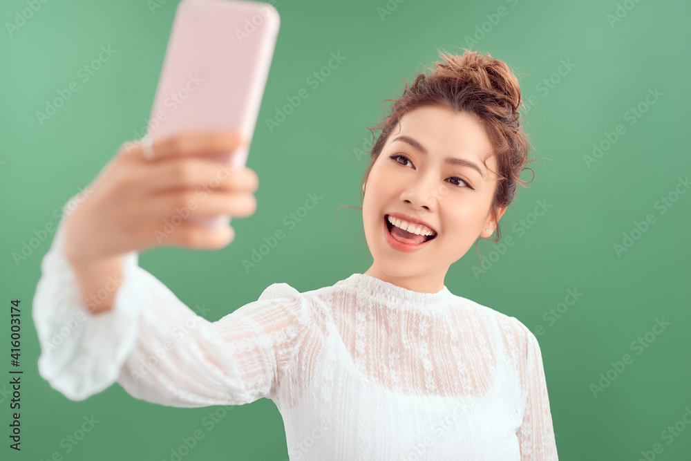 Lovely young alluring woman posting photo online, video-calling friend, holding smartphone raised as taking selfie, tilt head making cute expression Lovely young alluring woman posting photo online, video-calling friend, holding smartphone raised as taking selfie, tilt head making cute expression