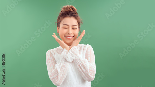 Photo portrait of excited woman with open mouth holding hands near face isolated on green colored background