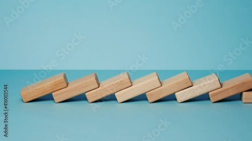 Domino effect, row of wooden domino falling down with yellow background.
