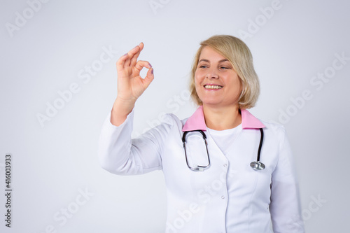 Closeup portrait friendly  smiling doctor with stethoscope  woman health care professional giving OK sign  isolated gray background. Patient visit. Positive face expression  emotion attitude