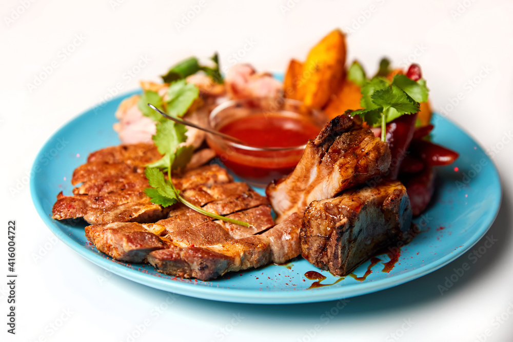 Meat platter with baked potatoes and tomato sauce on white background. Close-up, selective focus