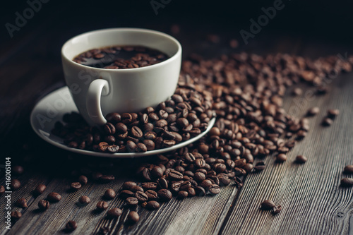 fragrant coffee beans on a wooden table and a cup with a hot drink on a saucer