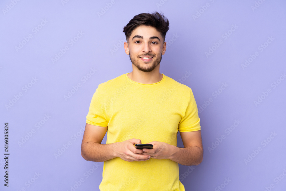 Arabian handsome man over isolated background sending a message with the mobile Arabian handsome man over isolated background sending a message with the mobile