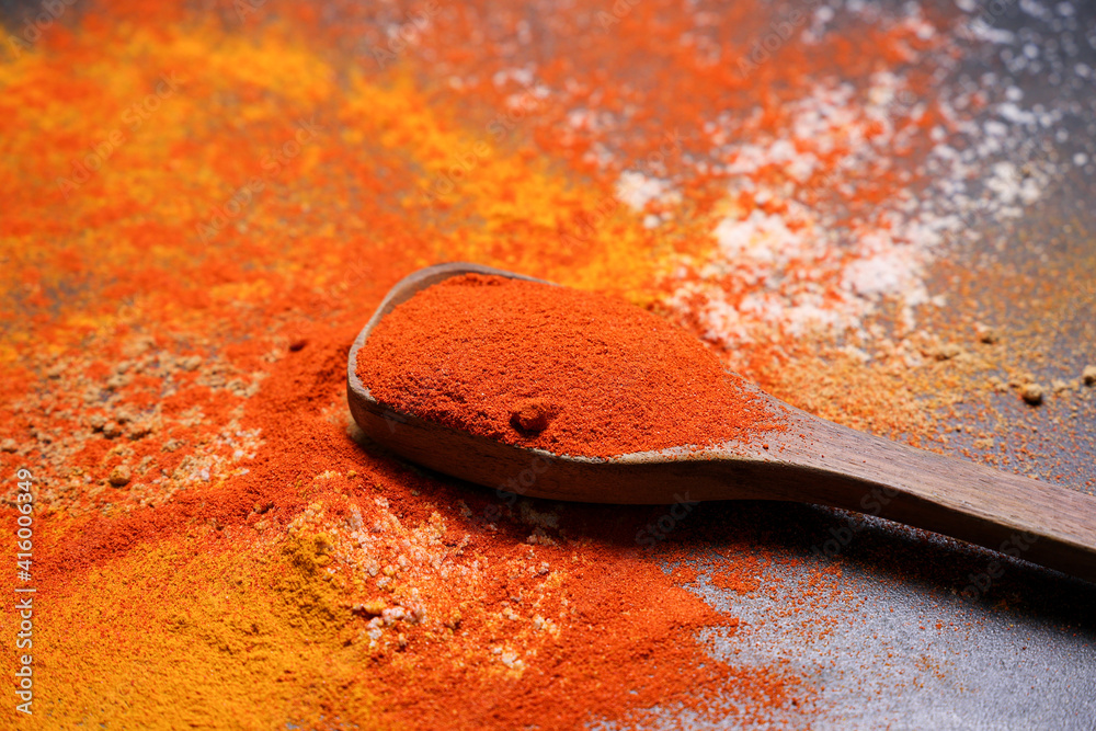 Indian spices red chilly , chili powder , paprika in wooden spoon scattered on black background