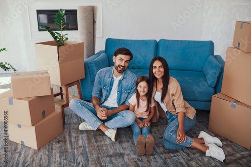 Cheerful couple and their child posing in their new house