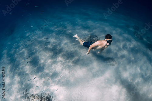 Male free diver glides underwater in clear ocean in Hawaii