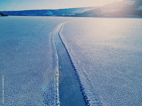 Ice skating road on the clear glassy ice of a large frozen lake with light snow on top of the ice. photo