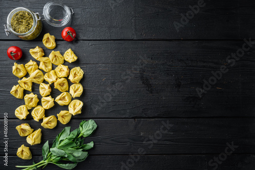 Raw Tortellini with basil and pine pesto, on black wooden table background, top view flat lay,  with copy space for text