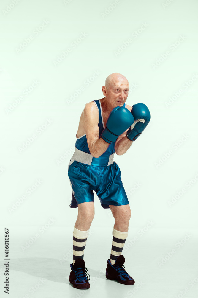 Champion. Senior man wearing sportwear boxing on studio background. Caucasian male model in great shape stays active and sportive. Concept of sport, activity, movement, wellbeing. Copyspace, ad.