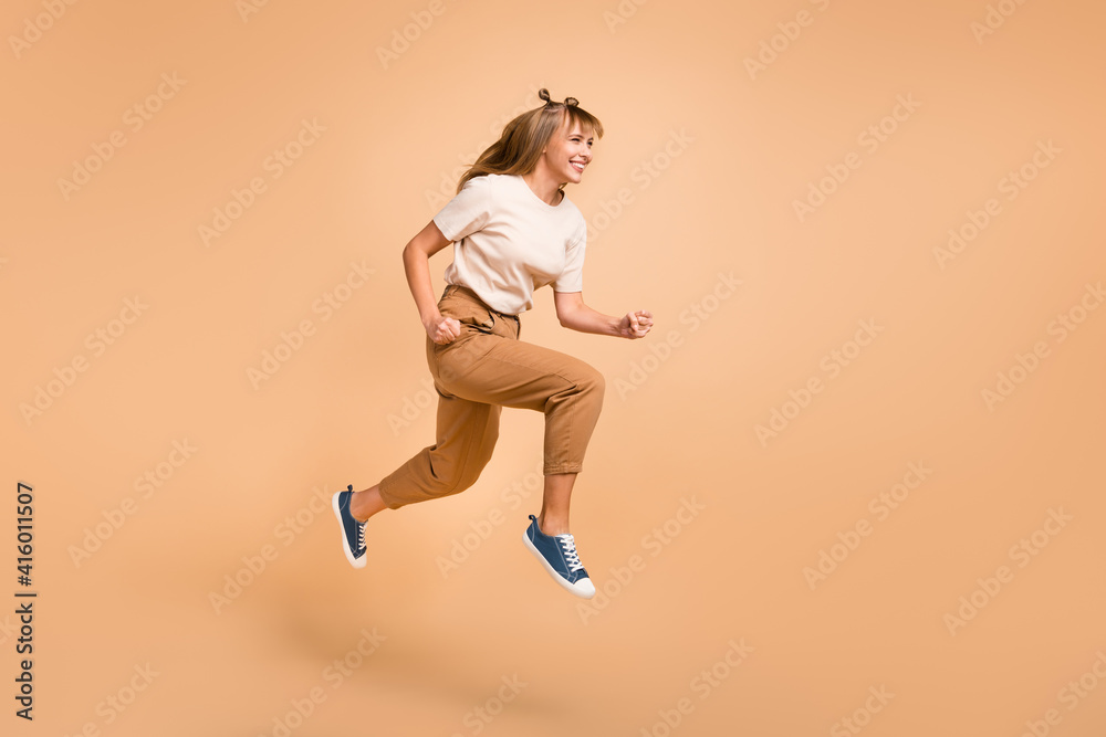 Full length profile photo of lady jump run wear t-shirt pants sneakers isolated beige color background