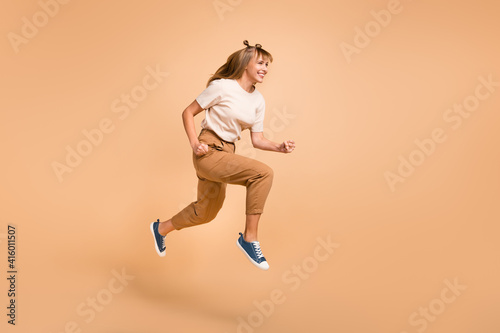 Full length profile photo of lady jump run wear t-shirt pants sneakers isolated beige color background