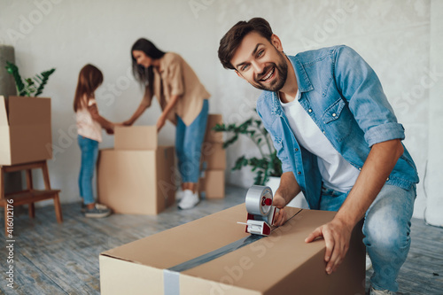 Caring father sealing boxes with family posessions before moving out photo