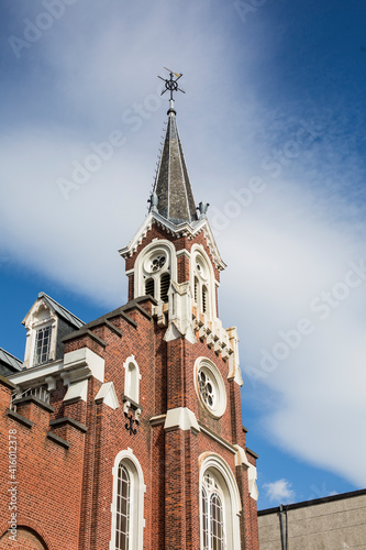 tower of a dutch style religious church in brussels, belgium, with blue sky and clouds