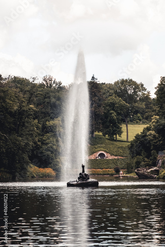 A snake-shaped fountain in the middle of a lake in a park