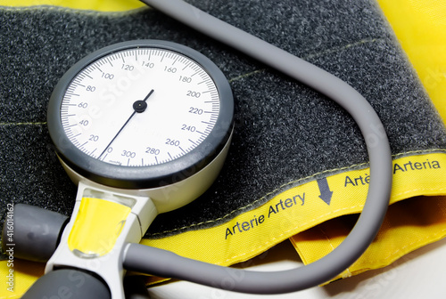 a portable sphygmomanometer resting on a yellow cuff for adults with a velcro closure.