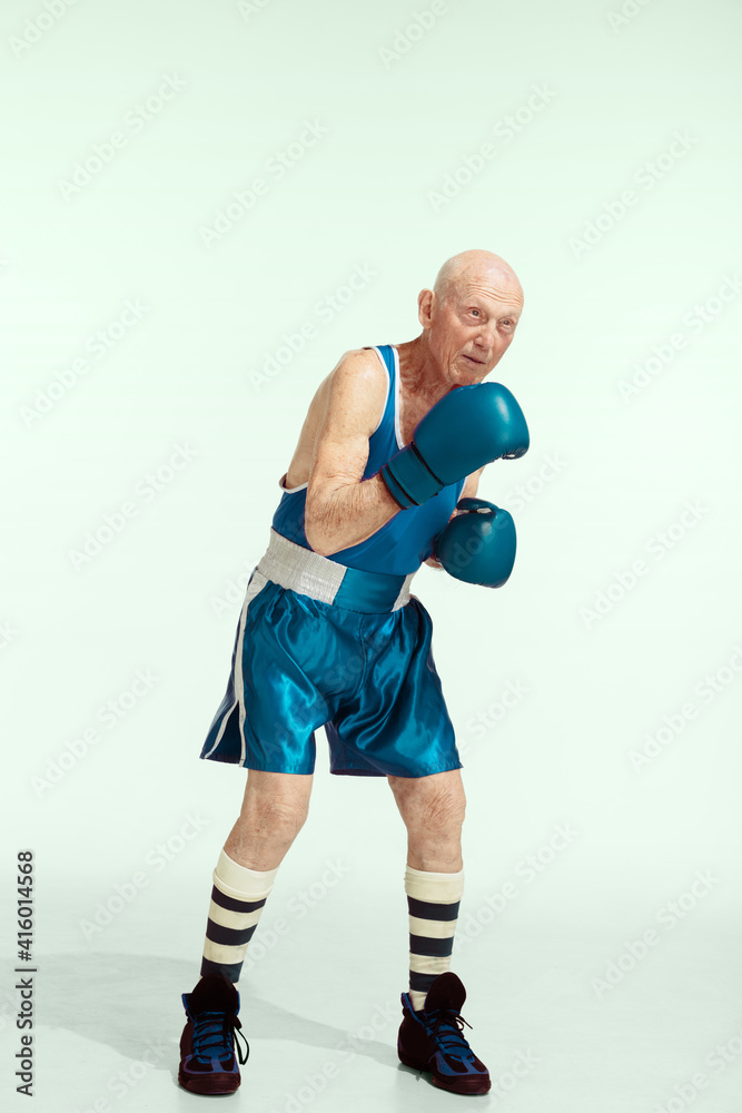 Kick. Senior man wearing sportwear boxing on studio background. Caucasian male model in great shape stays active and sportive. Concept of sport, activity, movement, wellbeing. Copyspace, ad.
