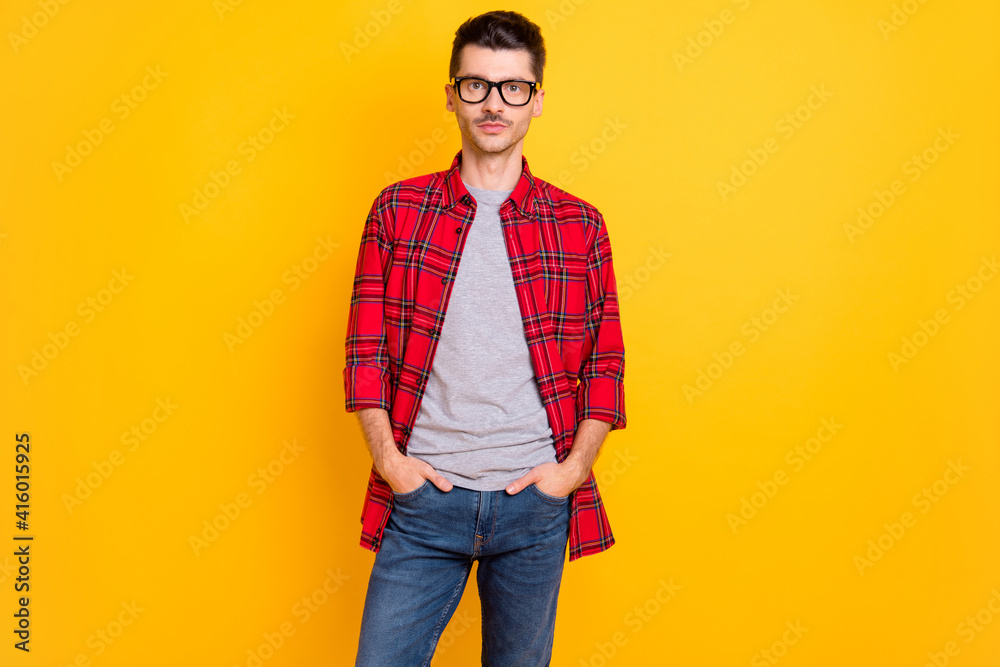 Photo of serious hipster man hold hands pockets wear red plaid shirt jeans isolated on vivid yellow color background Photo of serious hipster man hold hands pockets wear red plaid shirt jeans isolated on vivid yellow color background