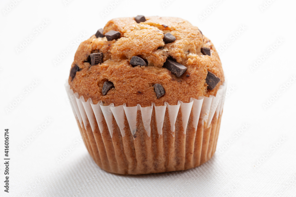 magdalena con virutas de  chocolate sobre fondo blanco, vista cenital. cupcake with chocolate chips on white background, overhead view.