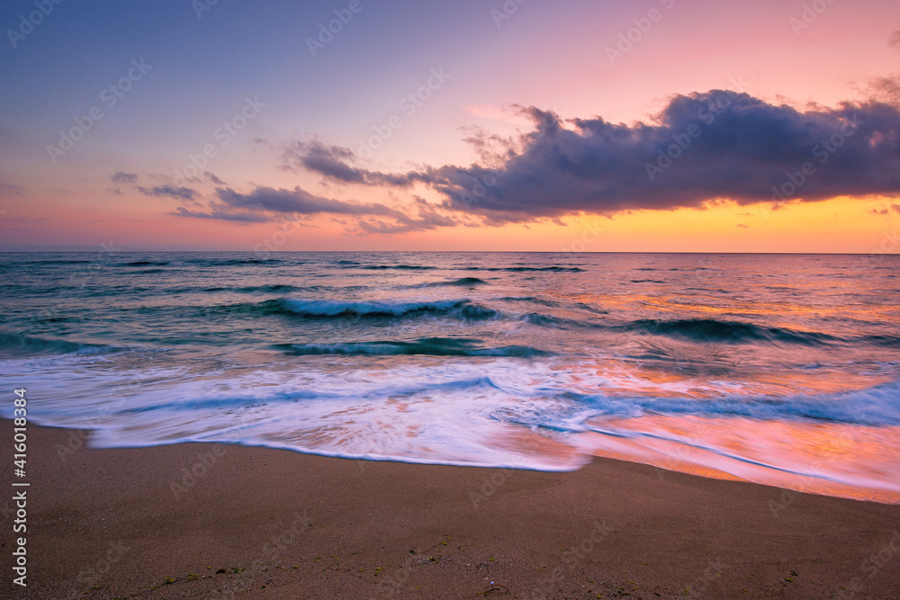 sea beach with dramatic sky at sunrise. beautiful vacation background. waves rolling on the sand in morning light