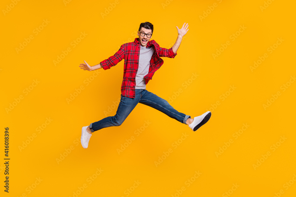 Full length photo of funny young man wear checkered shirt eyewear jumping high isolated yellow color background
