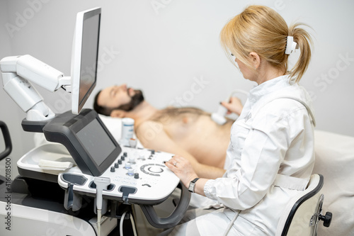 Doctor examining liver of male patient with ultrasound scan in medical clinic. Health and wellness concept.