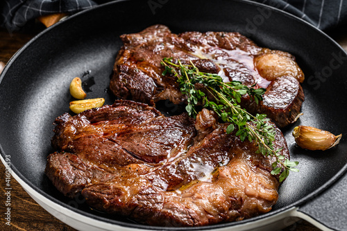 Roasted rib eye steaks in a pan. Dark wooden background. Top view