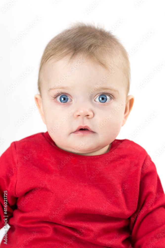 A child with wide open eyes looks directly white background.