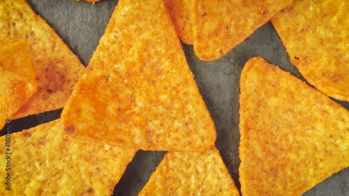 tortillas chips rotate on black background. Yellow triangle shaped tortilla chips on black. Mexican salty snack base of corn. Tasty nachos for appetizer. traditional crunchy corn chips.