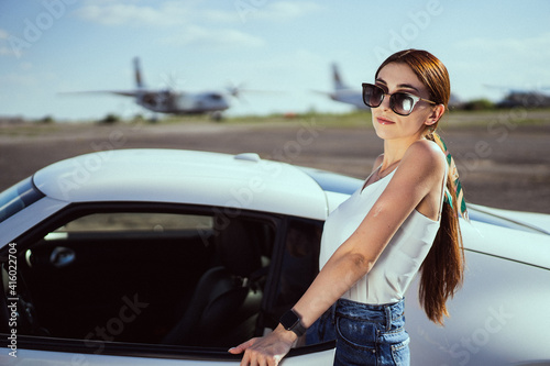 Beautiful girl in sunglasses on the background car and airplane 