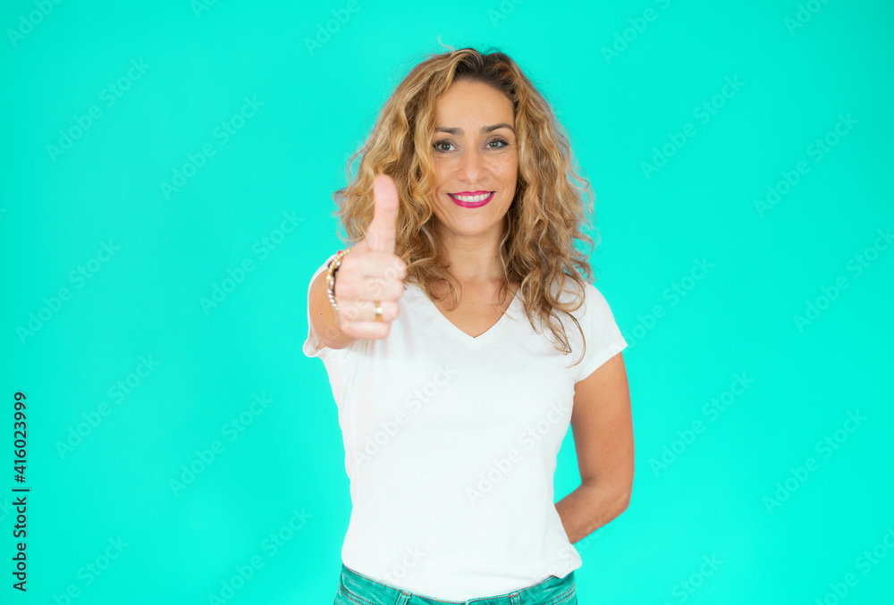 Fototapeta premium Portrait of happy young woman with thumb up over green background.