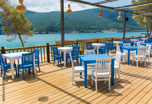 Fototapeta Naklejka Na Ścianę i Meble -  Outdoor  Greek  Restaurant with Blue Chairs and Tables and Sea View