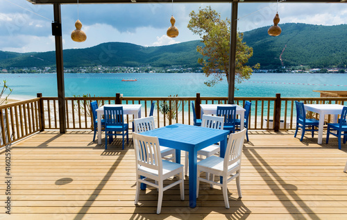 Fototapeta Naklejka Na Ścianę i Meble -  Outdoor  Greek  Restaurant with Blue Chairs and Tables and Sea View