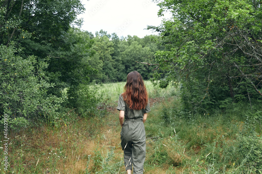 happy brunette woman in overalls on the meadow back view happy brunette woman in overalls on the meadow back view