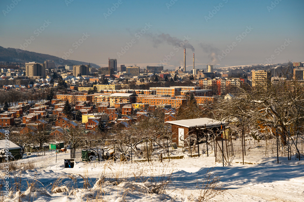 Snowy outskirts and downtown view of city Zlin with typical red brick houses and heating plant chimney on background. Czech republic.