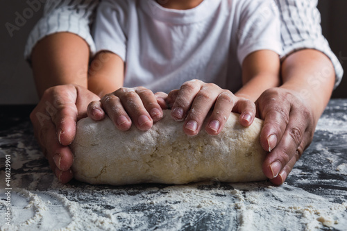 Close-up of mother's and daughter's hands kneading dough together.