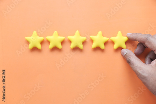 Customer review concept. Rating golden stars on orange background 