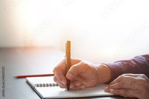 man hand using writing pen memo on notebook paper or letter, diary on table desk office. Workplace for student, writer with copy space. business working and learning education concept.
