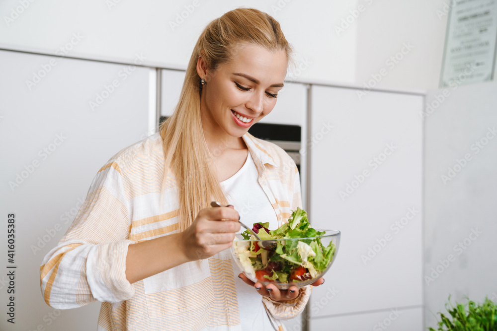 Joyful blonde woman smiling while preparing fresh salad Joyful blonde woman smiling while preparing fresh salad