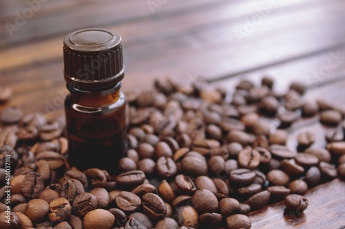 Coffee essential oil in a glass bottle  coffee beans on a wooden background 