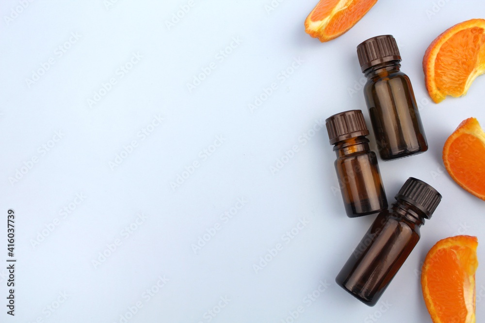 Tangerine essential oil in glass bottle, orange citrus on blue background Tangerine essential oil in glass bottle, orange citrus on blue background
