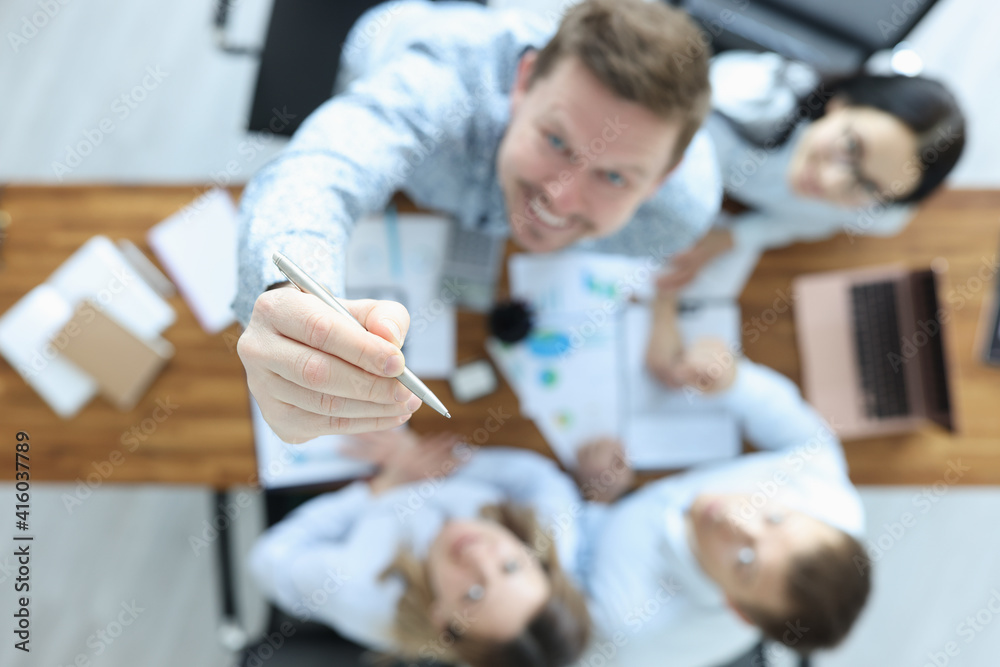Group of business people are sitting at table top view. Man pointing pen up Group of business people are sitting at table top view. Man pointing pen up
