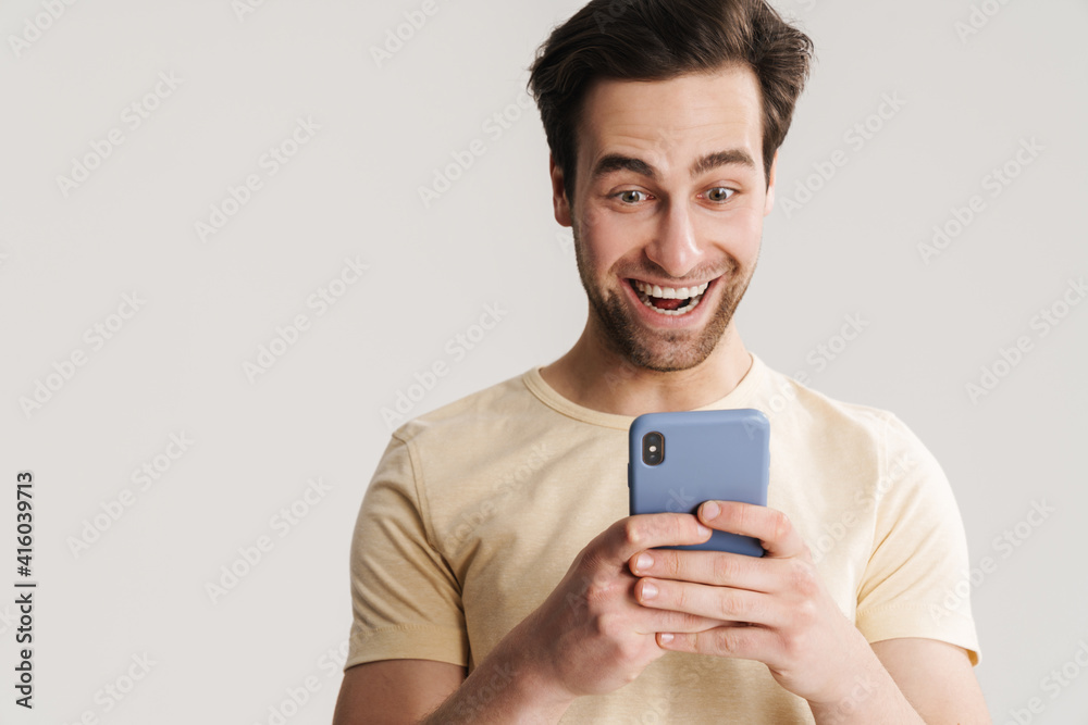 Excited handsome guy smiling and using mobile phone