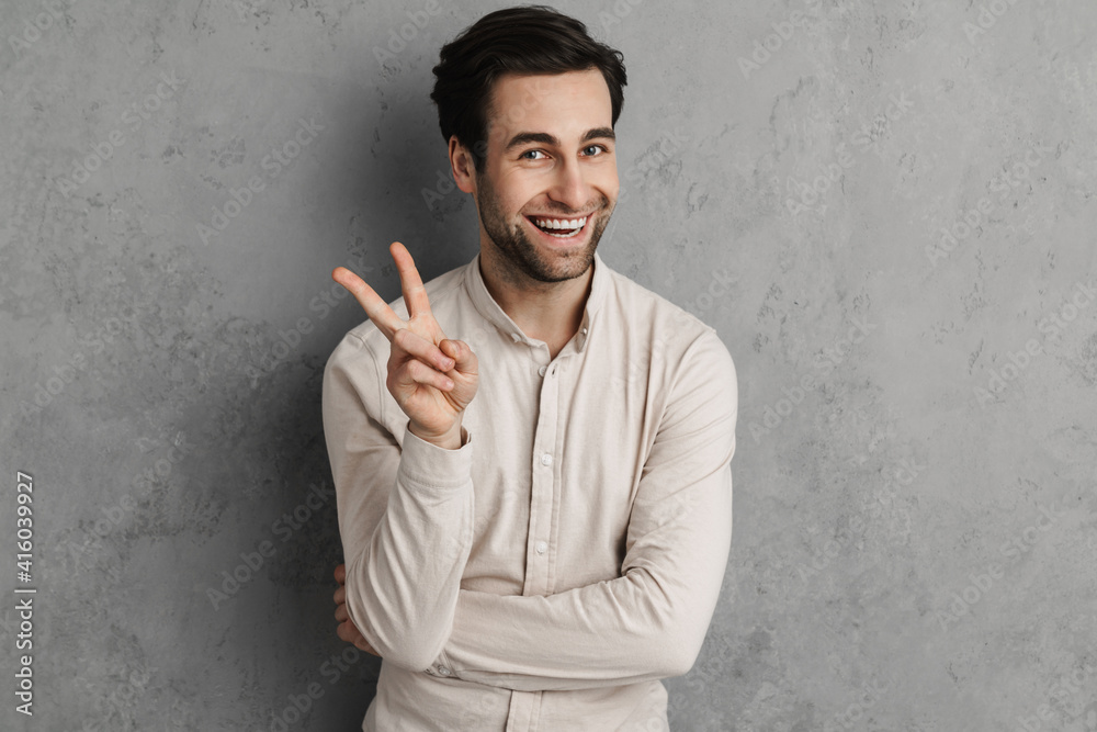 Joyful handsome guy smiling and showing peace sign Joyful handsome guy smiling and showing peace sign