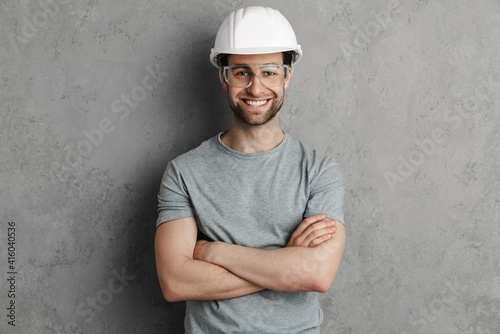 Joyful builder man in helmet and goggles smiling and looking at camera