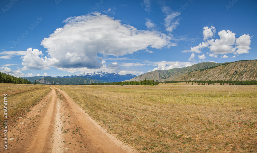 Mountain steppe road on a summer day, beautiful cloudy sky