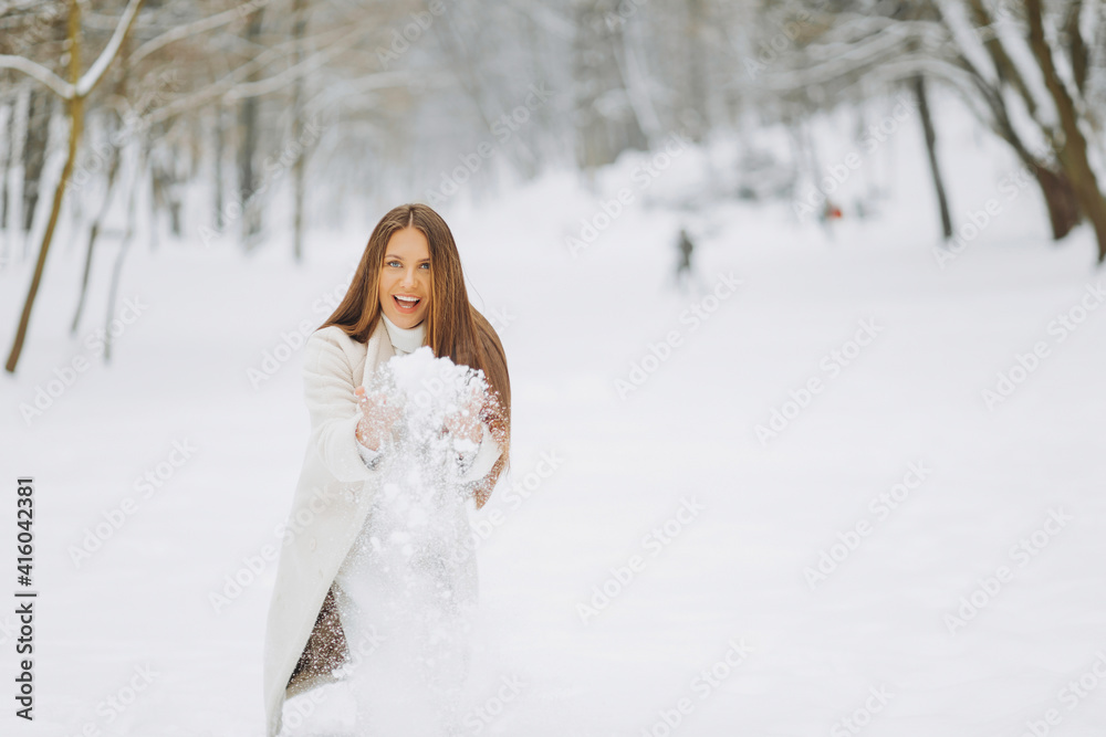Winter portrait of a merry young woman playing with snow at the park Winter portrait of a merry young woman playing with snow at the park