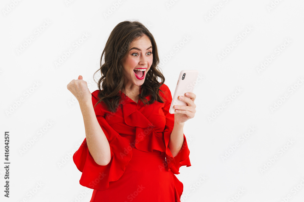 Naklejka premium Cheerful young woman in red dress using mobile phone