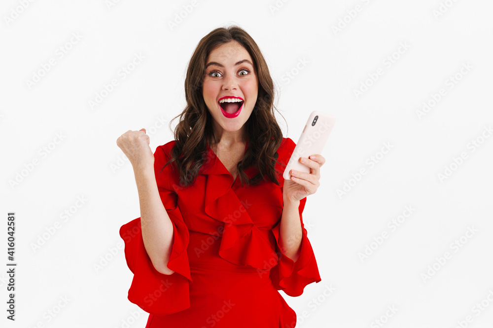 Naklejka premium Cheerful young woman in red dress using mobile phone